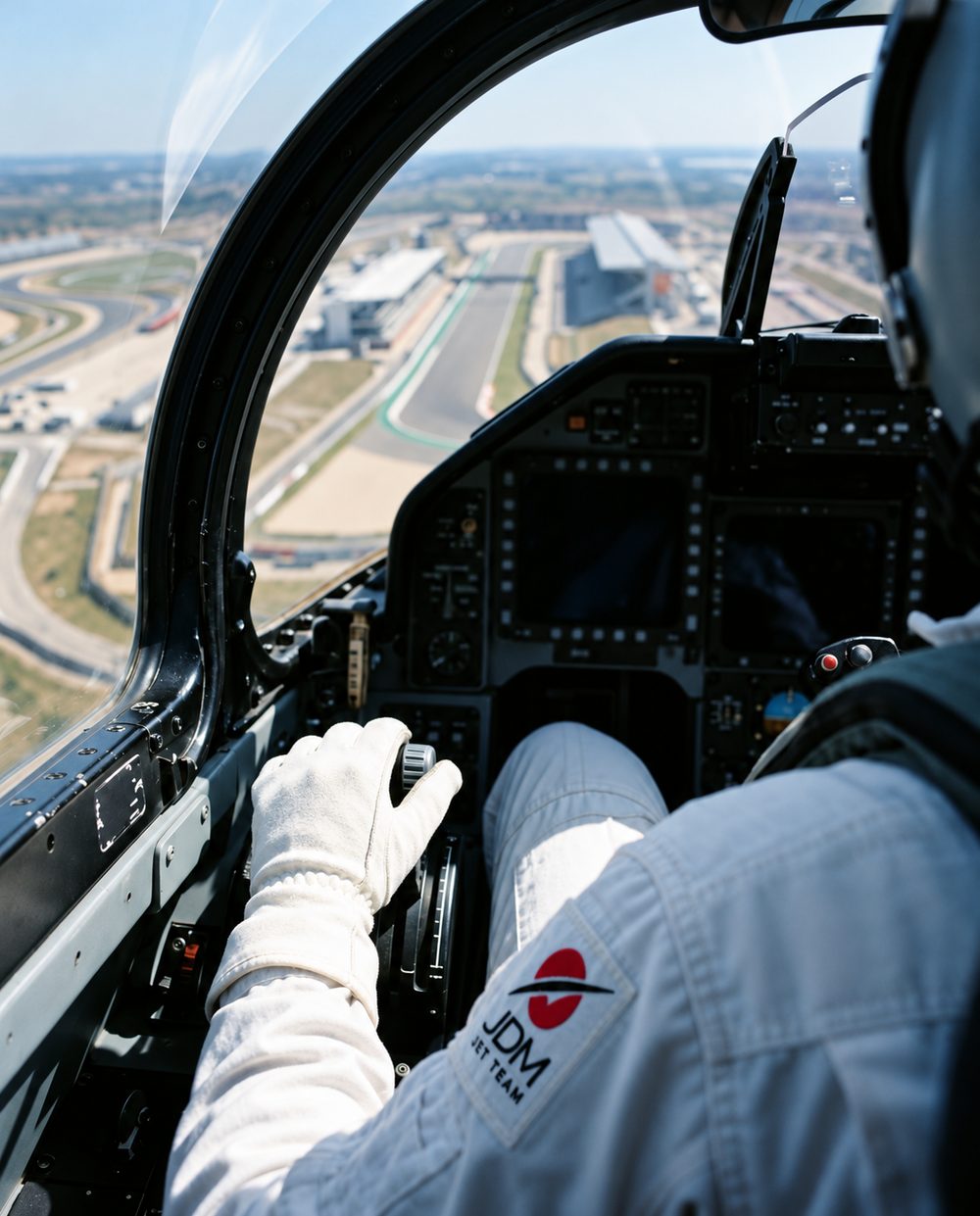 Cockpit, over the pilot's shoulder, the nozzle lever by the throttle, circuit below through the canopy.